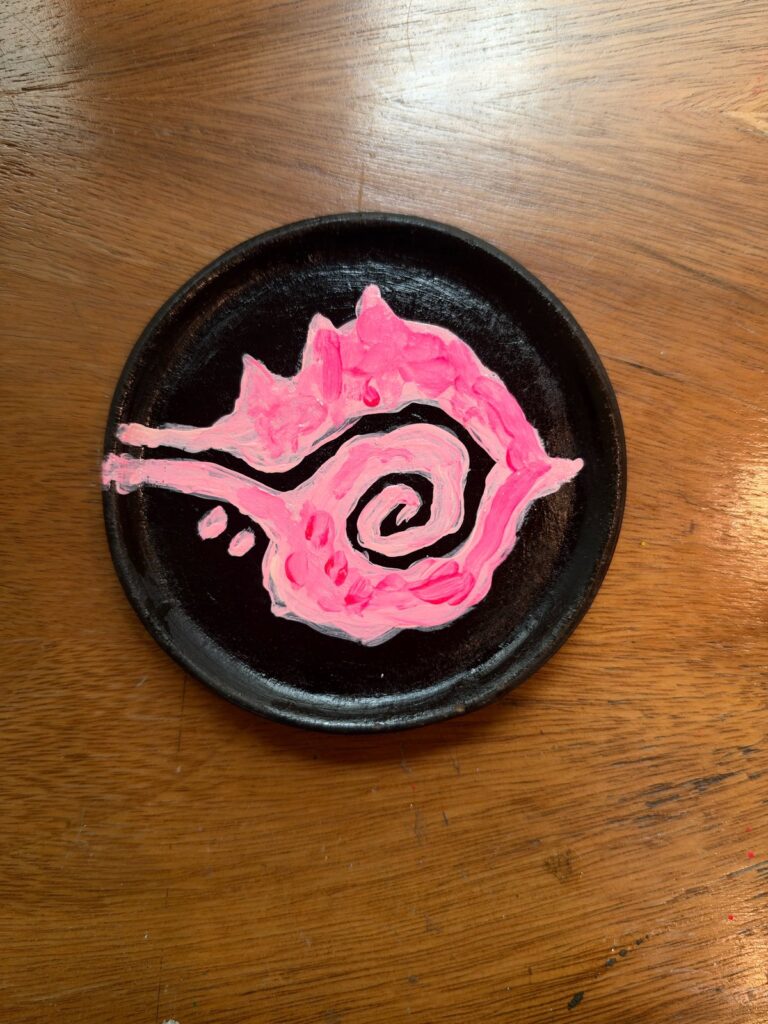 Caracol en espiral pintado en acrílico rosa magenta sobre plato de barro negro oaxaqueño